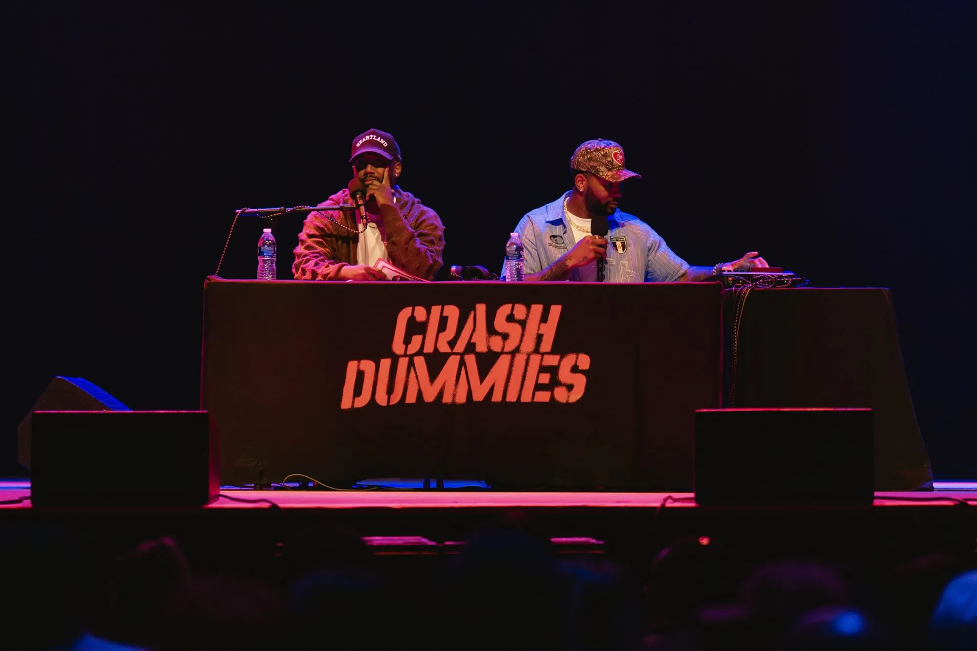 Both hosts at the Crash Dummies desk under red stage light