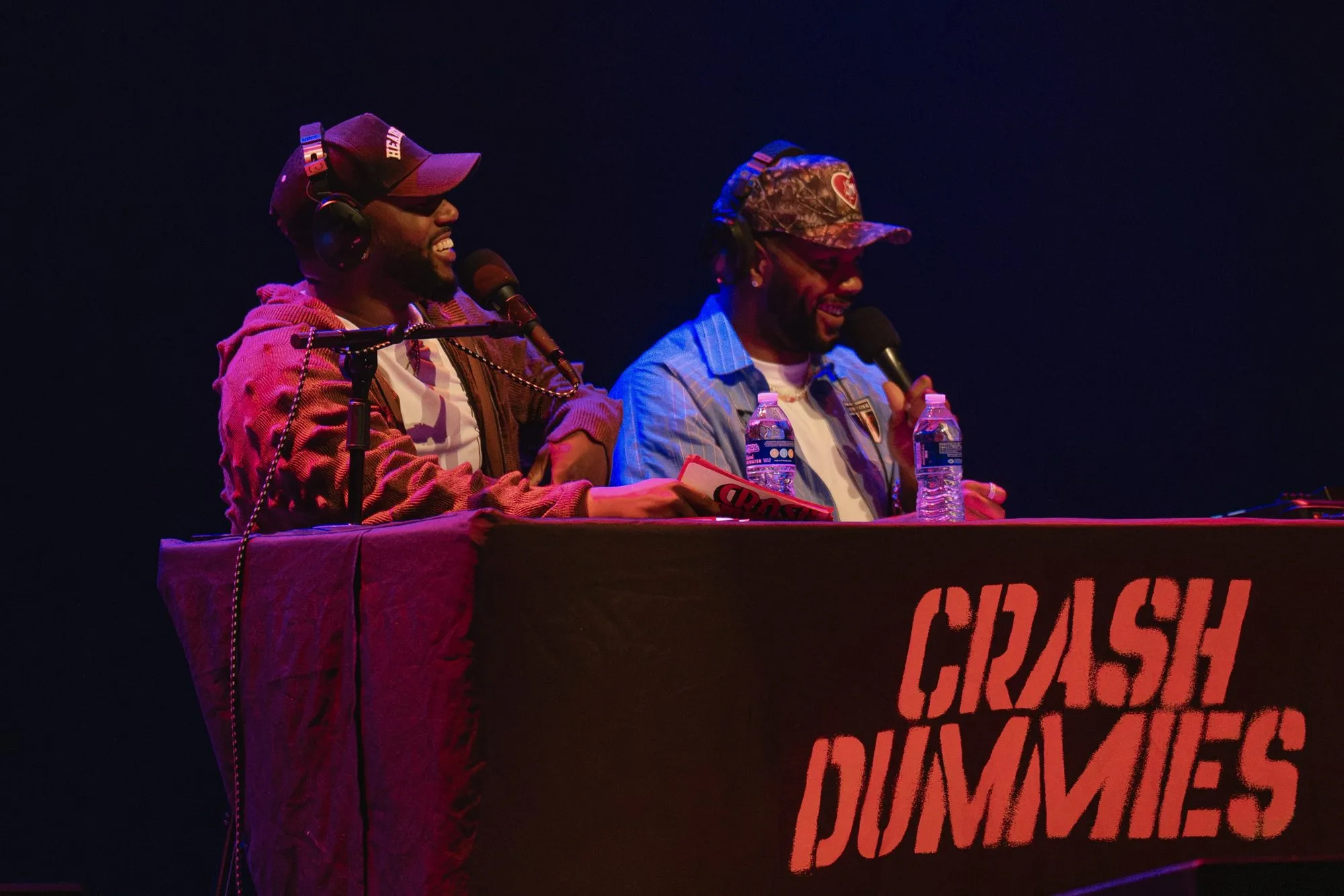 Close-up of both hosts in headphones, laughing