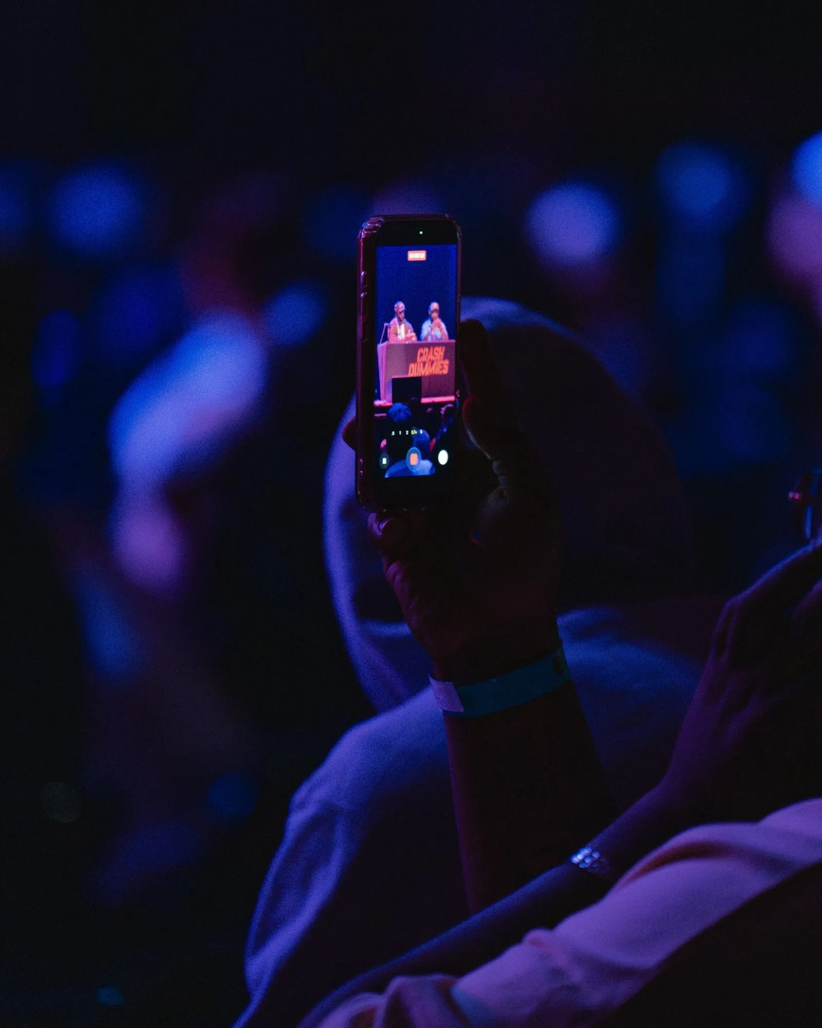 A fan records the hosts on their phone in the crowd