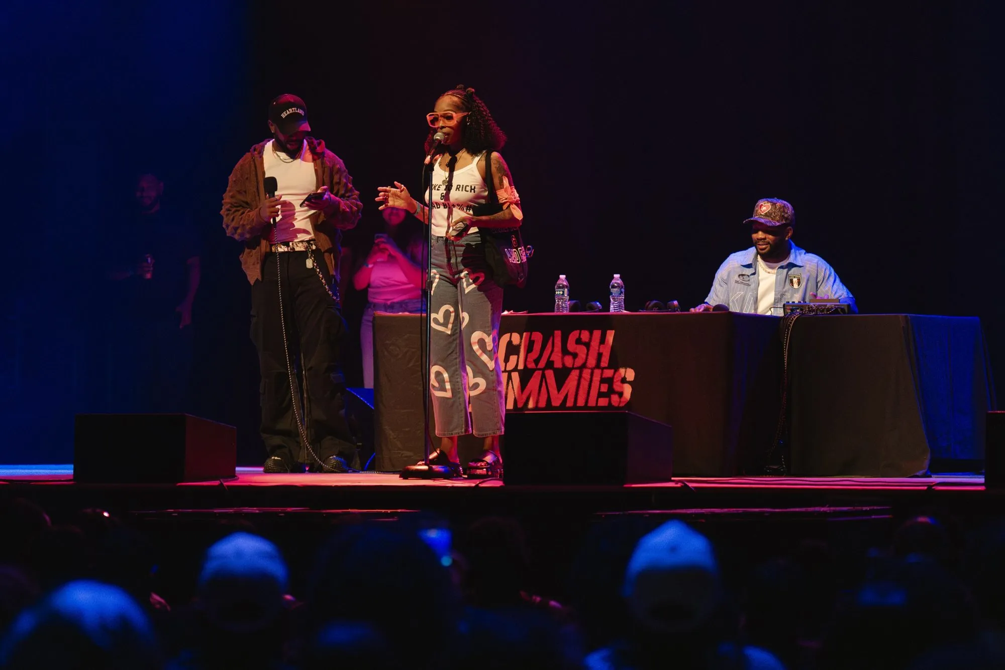 A fan speaks at the mic stand while the hosts look on