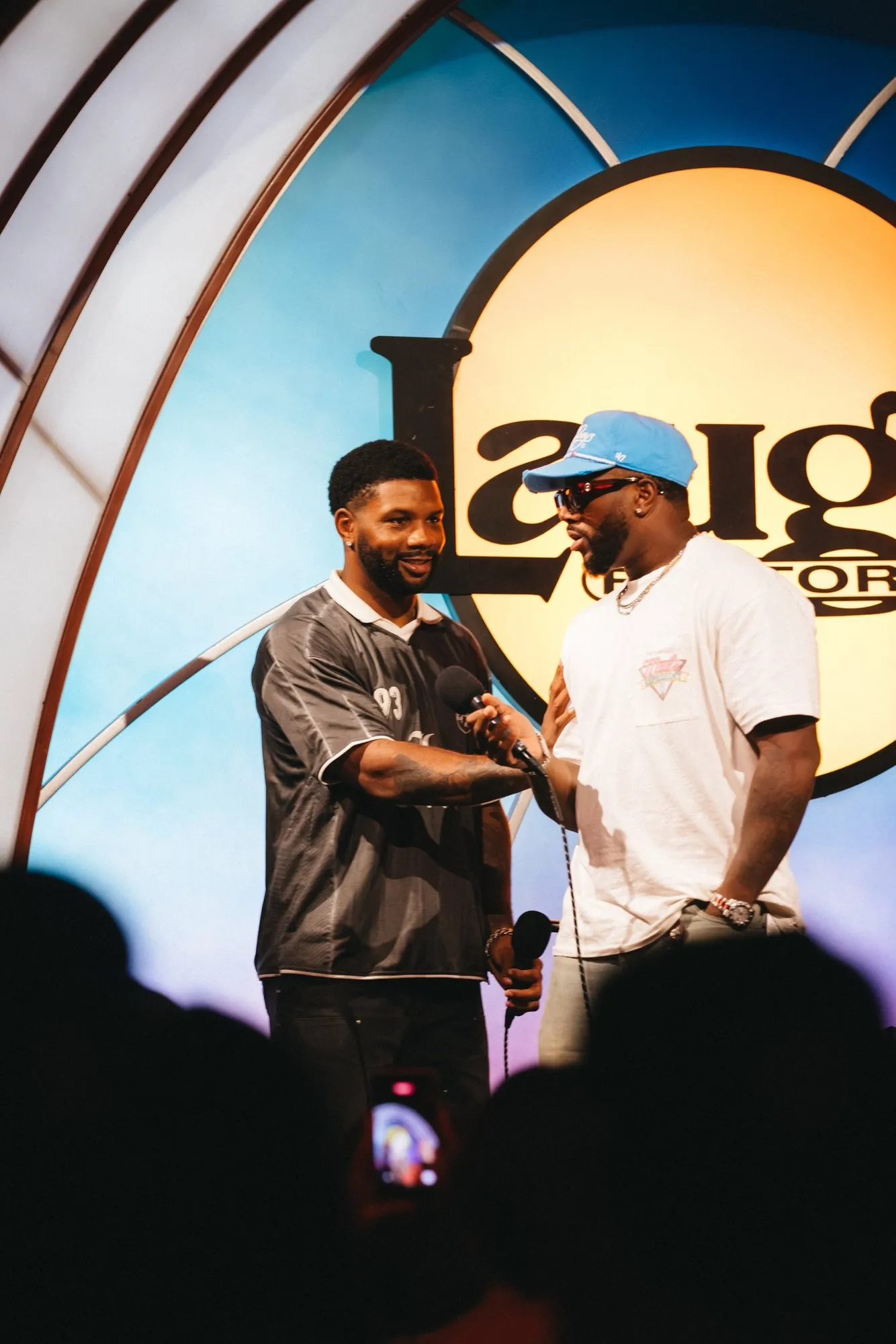 A host and a guest share a laugh on stage